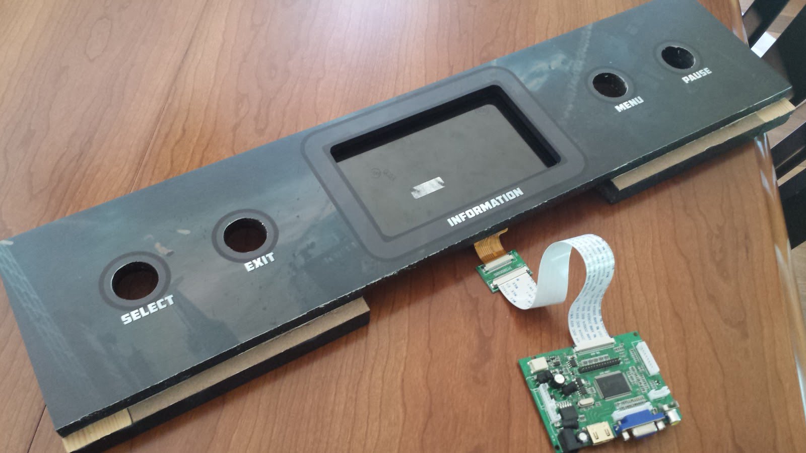 Administration panel with artwork applied. The screen is in place, with the screen control board attached to a ribbon, visible beneath the panel.