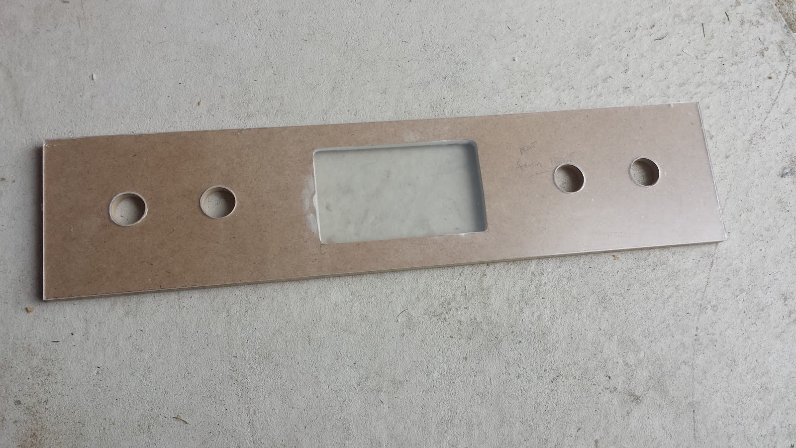 Arcade administration panel with four button holes drilled, and an opening cut out for a screen. It is undecorated MDF. Plexiglass covers the material.