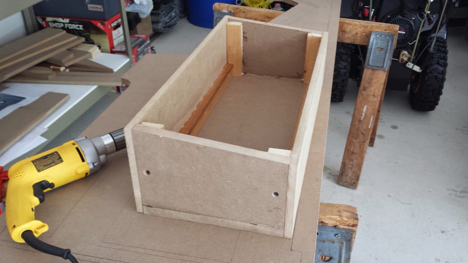 As assembled arcade control panel box (minus the top piece), sitting on a workspace next to a power drill