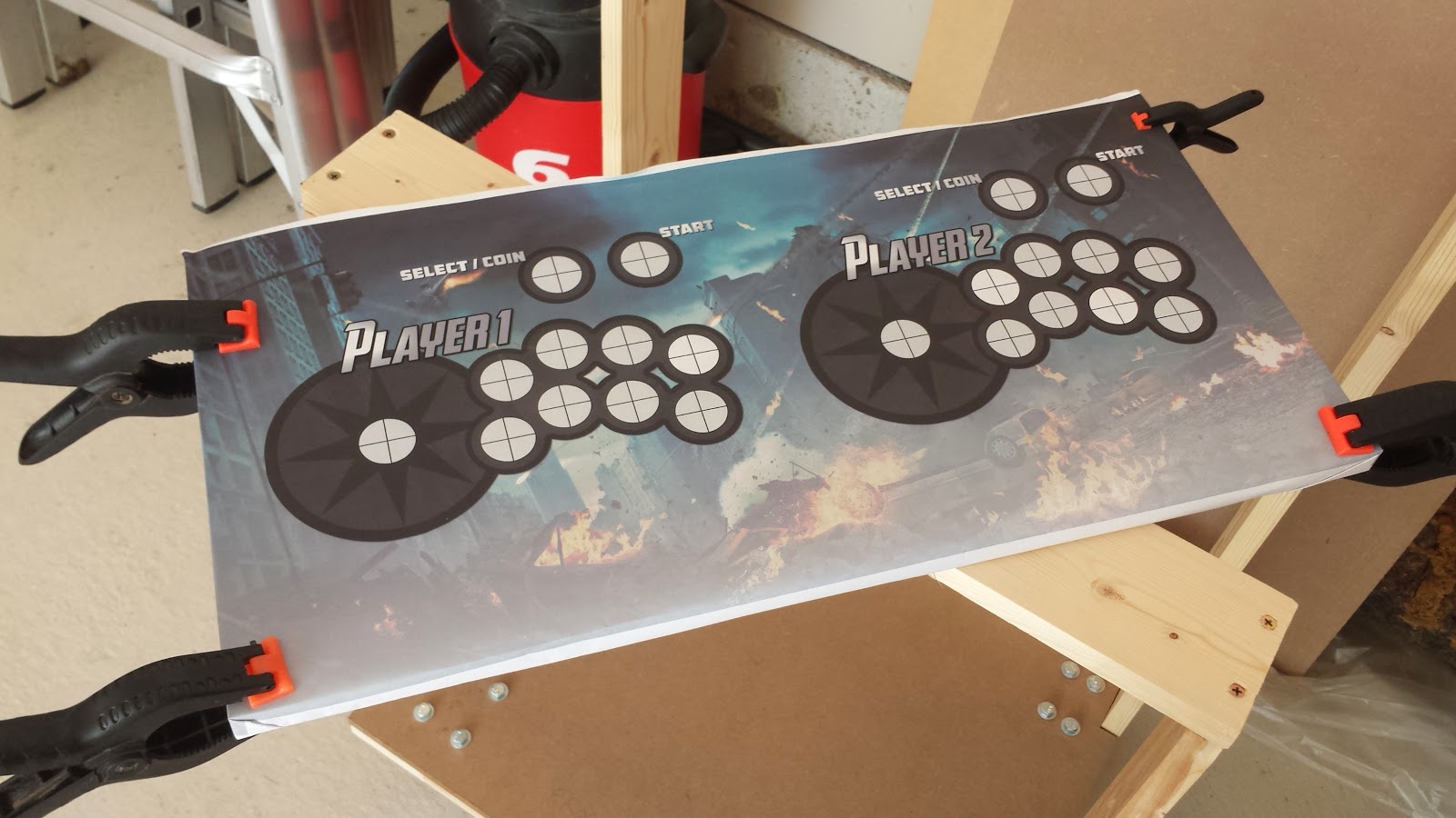 Paper print-out of control panel graphics, being held onto MDF board wood four clamps