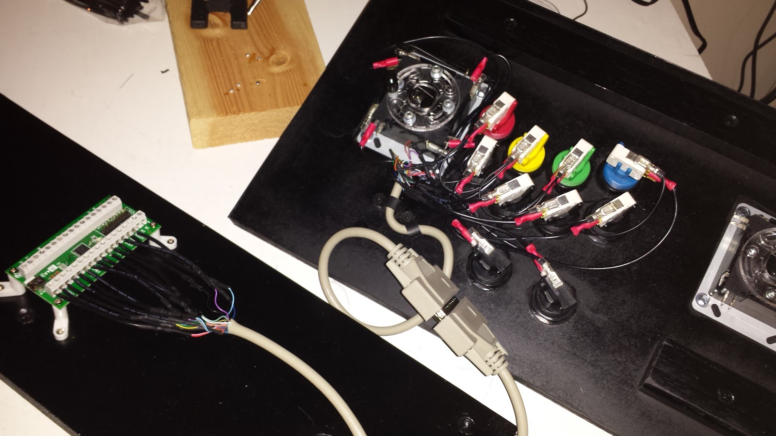 Underside of an arcade control panel, with buttons wired up to an IPAC-2 Encoder. The wires originate from a parallel cable, and the male & female ends are used to connect the IPAC end of the wires to the buttons.