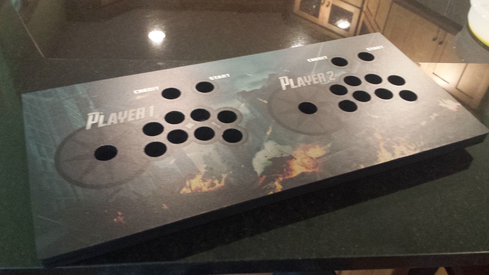 Control panel lying on a granite countertop. All of the button & joystick holes have been cut away.