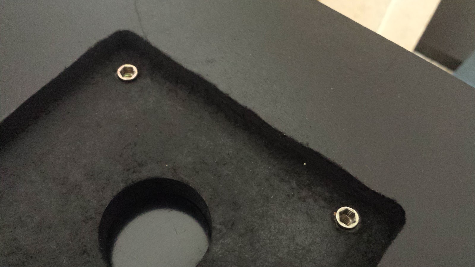 The underside of the control panel, painted black. Inside the square depression made to mount the joystick, brass EZ-Lok inserts have been installed in the corner.