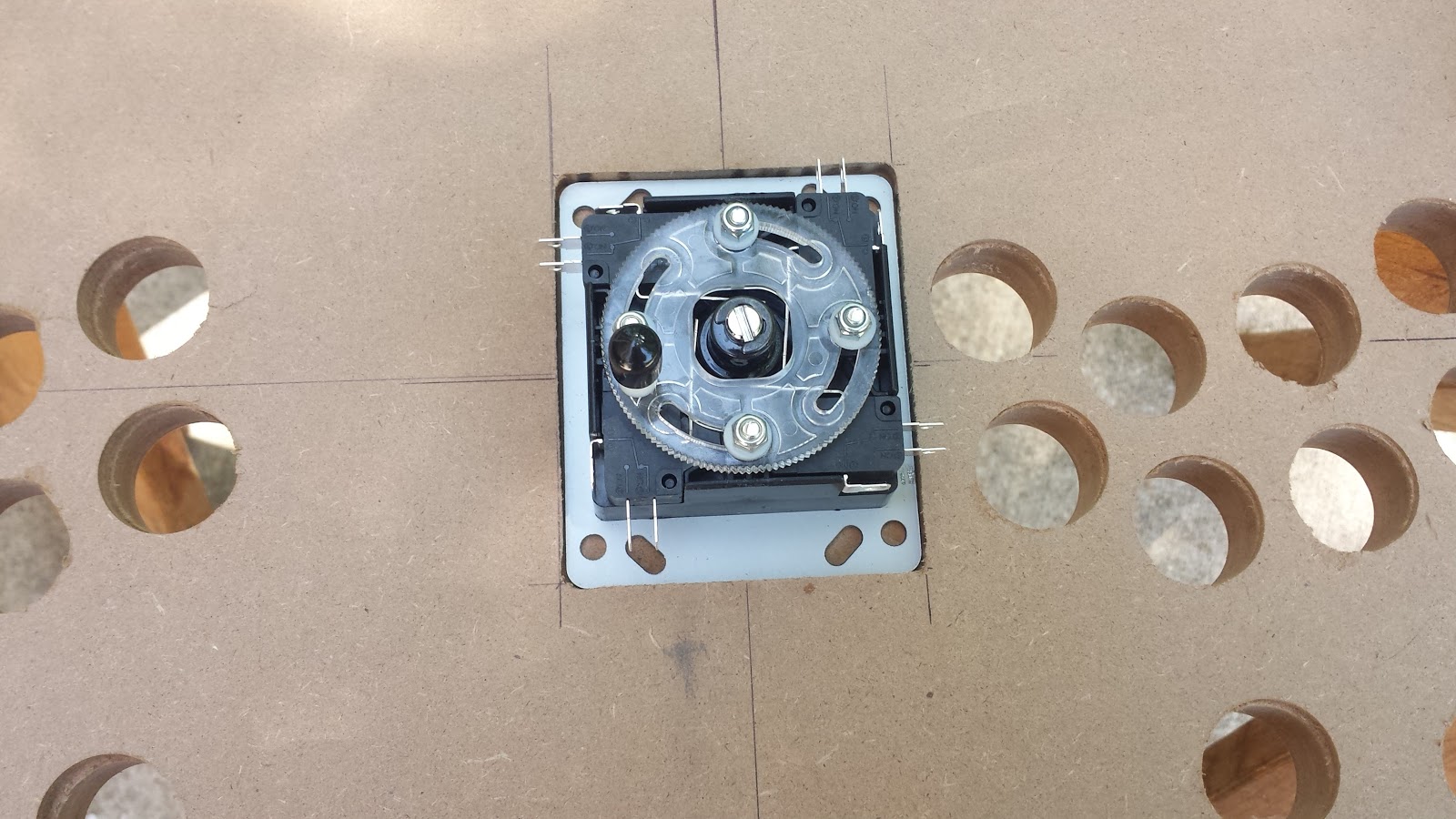 Underside of control panel. The button holes have been drilled. A joystick is seated inside a square depression created using a router.